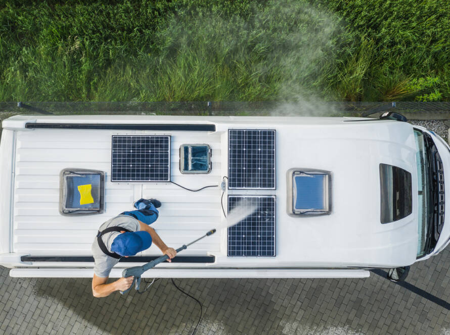 Men Pressure Washing RV Camper Van Roof Equipped with Solar Panels