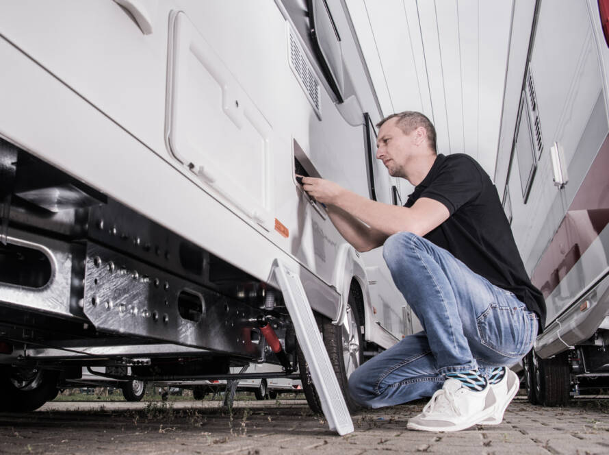 RVing Theme. Caucasian Men in His 40s Preparing His Travel Trailer For the Season Inside RV Storage. Looking Inside Refrigerator Compartment.
