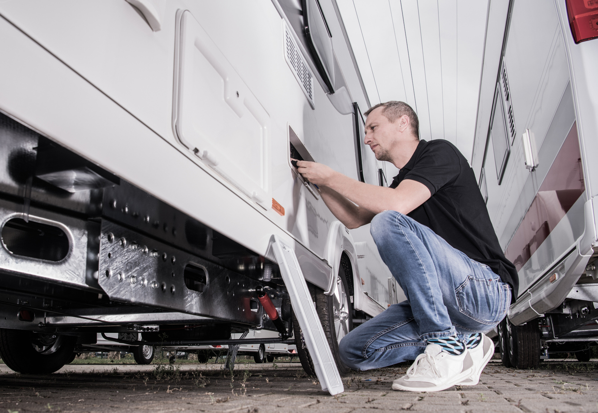 RVing Theme. Caucasian Men in His 40s Preparing His Travel Trailer For the Season Inside RV Storage. Looking Inside Refrigerator Compartment.